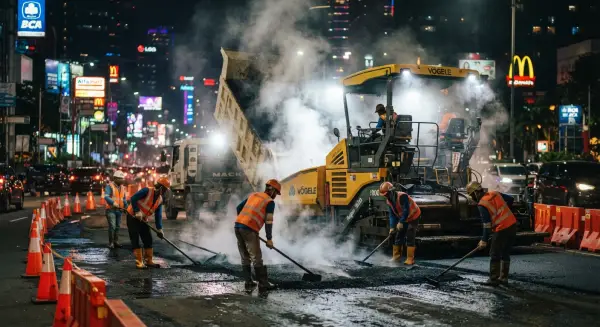 kontraktor aspal dari PT. Mitra Jalan Raya mengerjakan proyek aspal di tengah kota pada malam hari